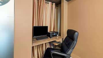 Una habitación con un escritorio, una computadora, una impresora y una silla de cuero negro.