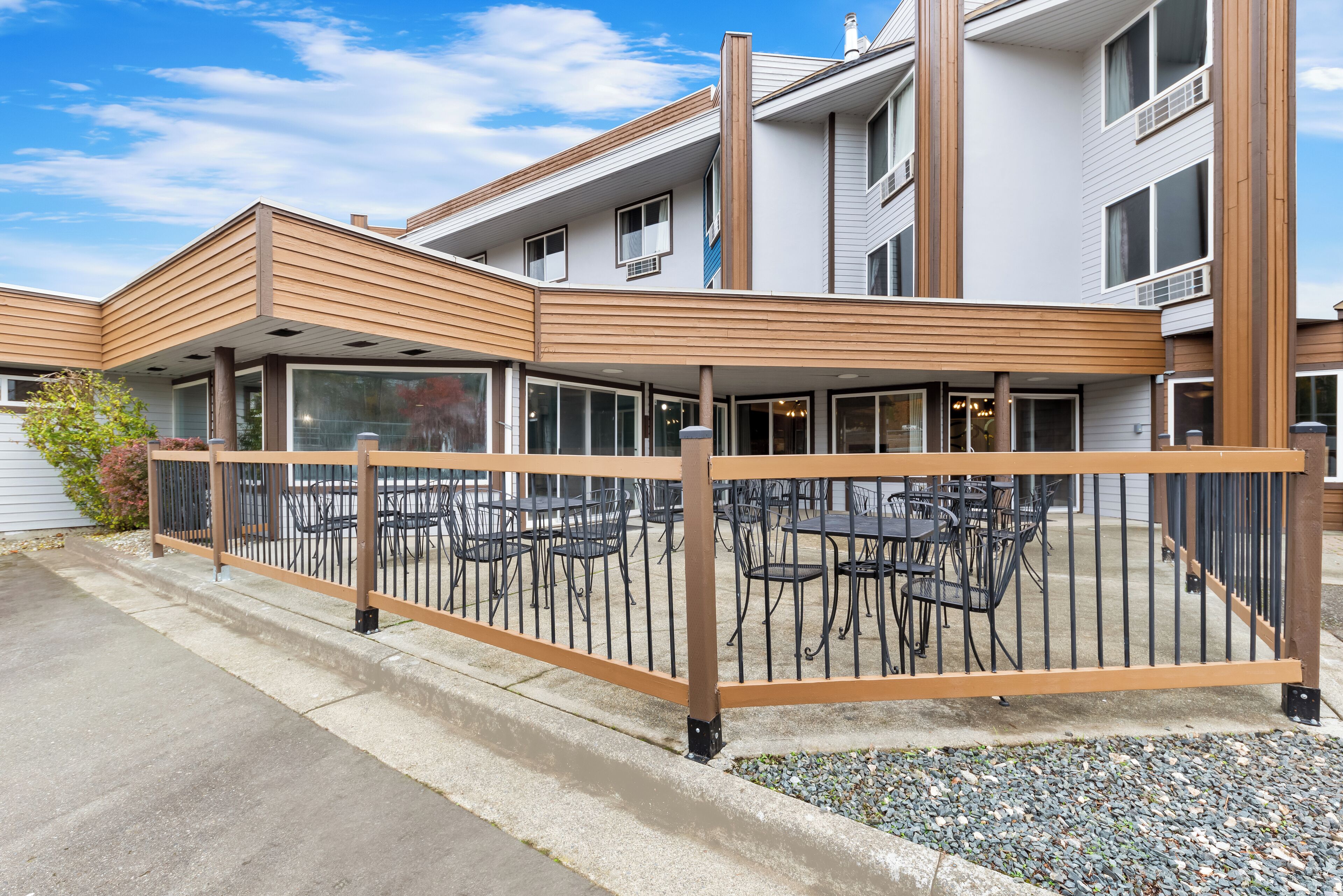 A modern building with a covered outdoor seating area, featuring tables and chairs.