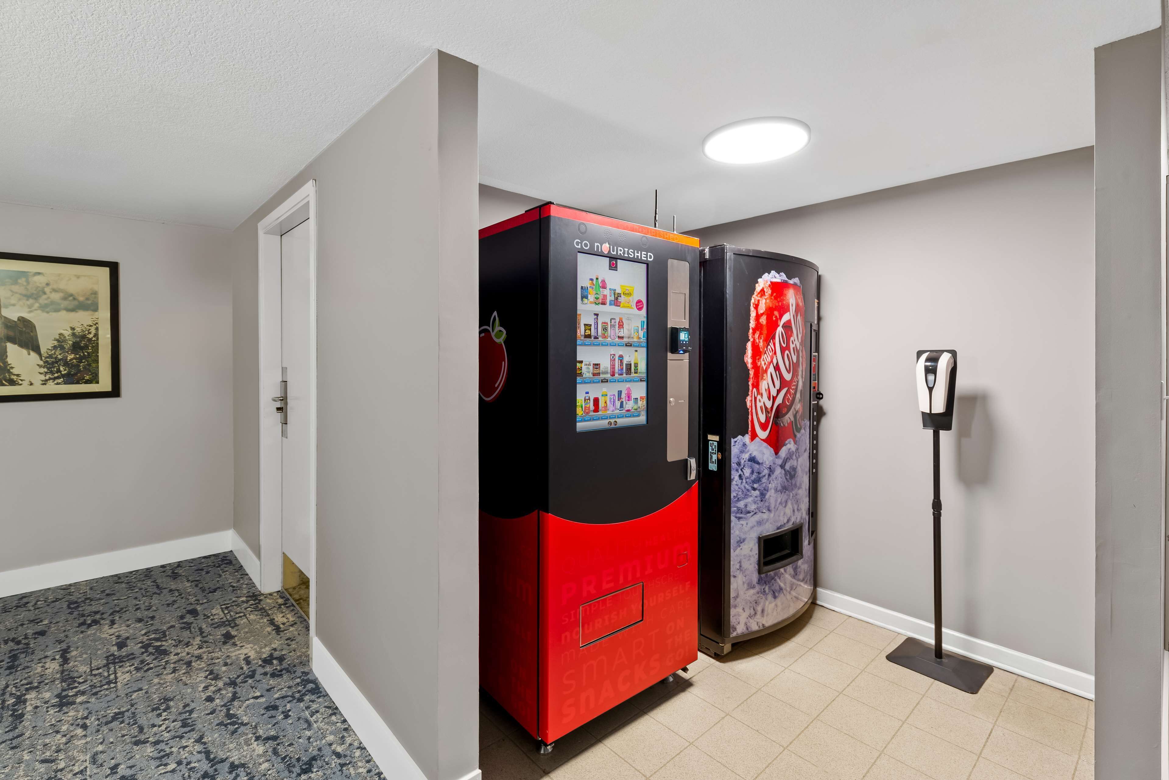 A hallway with vending machines, a door, and a framed picture on the wall.