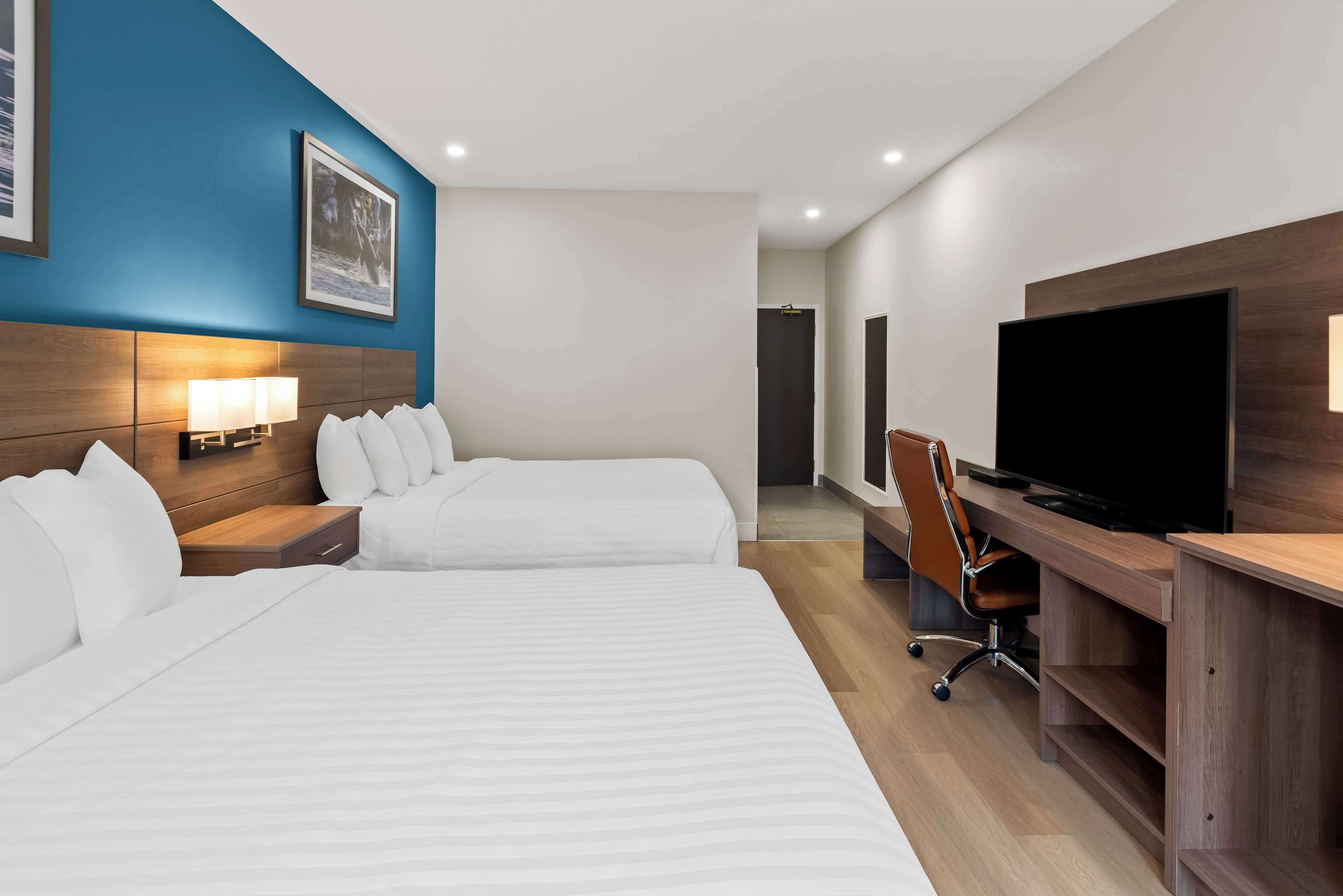 Ein Hotelzimmer mit zwei Betten, einem Schreibtisch mit Fernseher und einem Sessel.