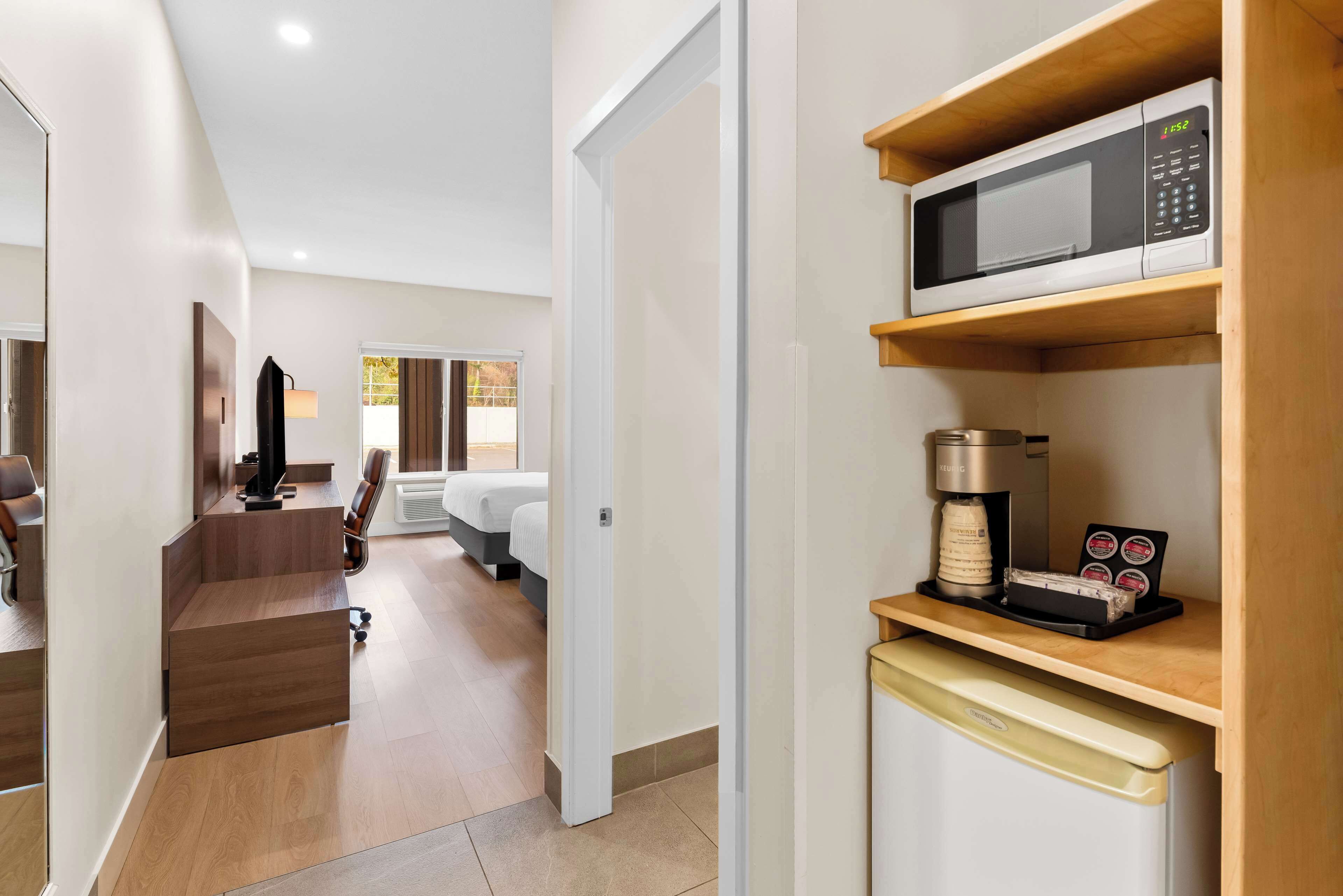 Una habitación de hotel moderna con kitchenette, una cama, un escritorio y vistas al exterior.