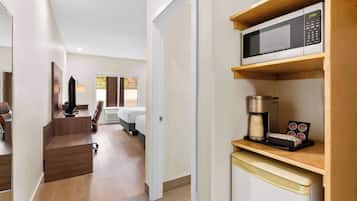 Una habitación de hotel moderna con kitchenette, una cama, un escritorio y vistas al exterior.