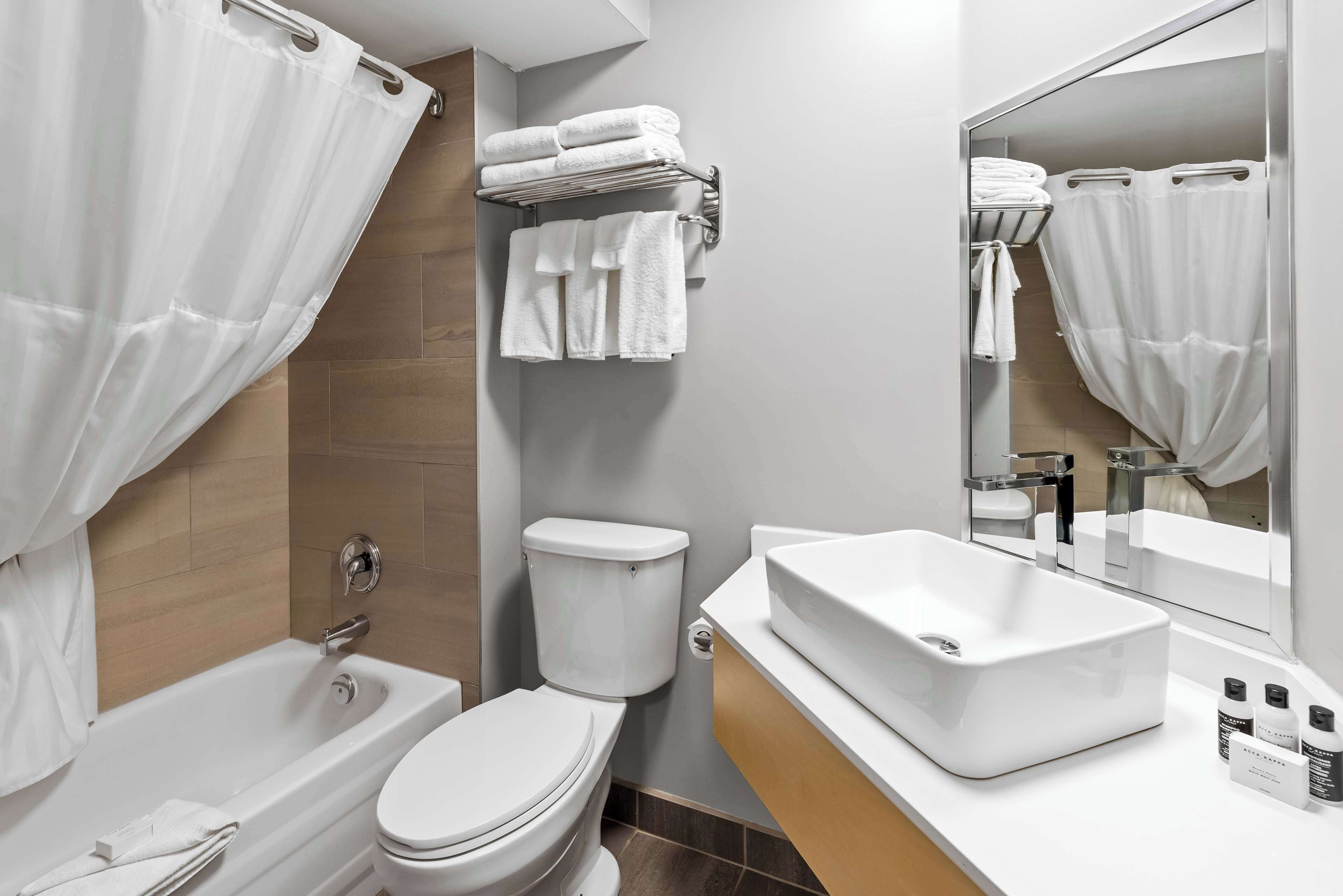 A modern bathroom with a bathtub, toilet, and a large mirror.