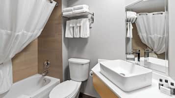 A modern bathroom with a bathtub, toilet, and a large mirror.