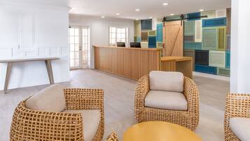 A reception area with a wooden desk, wicker chairs, and a colorful wall.