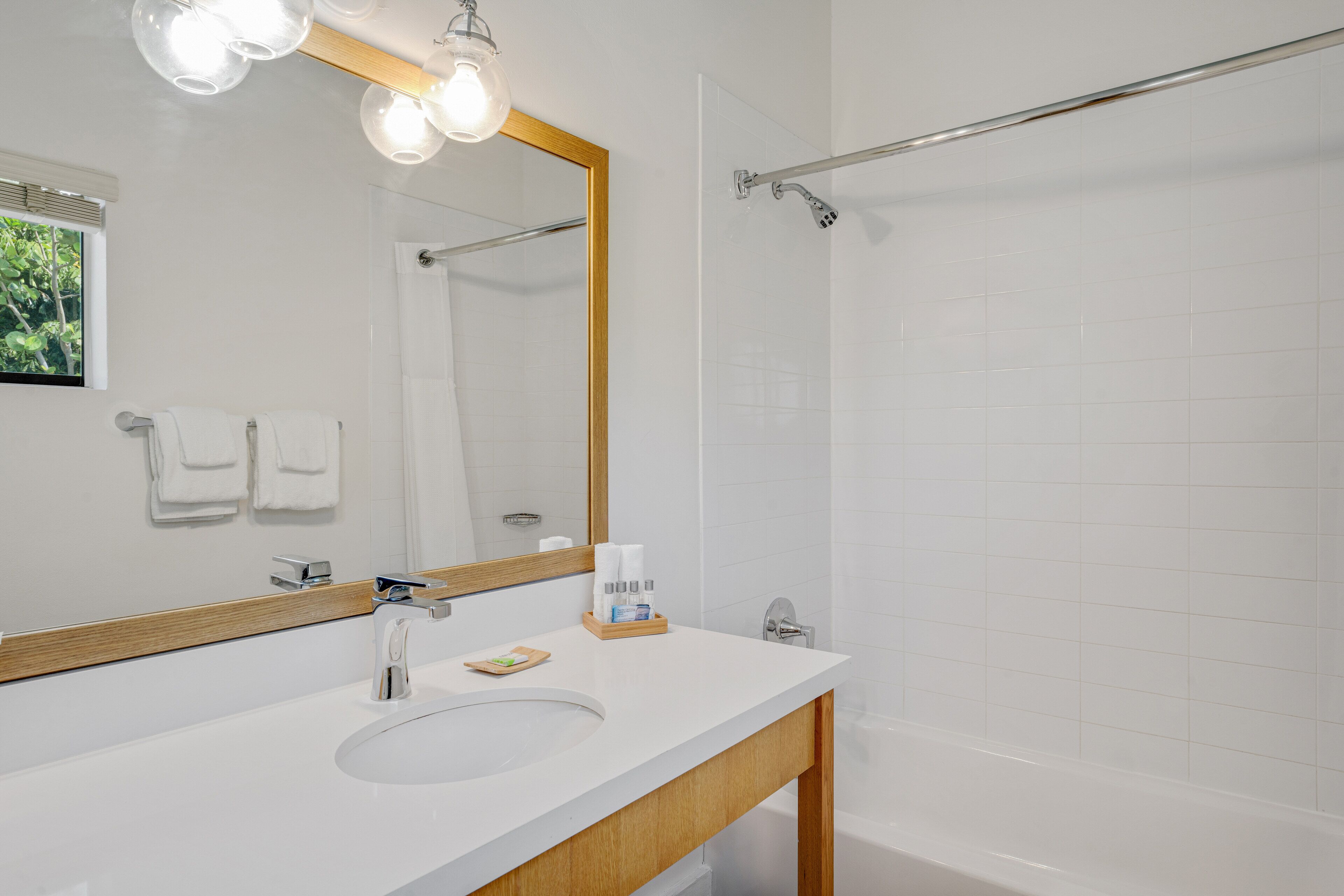 Un bagno moderno con un lavandino bianco, uno specchio grande e uno spazio doccia.