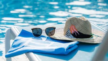 Escena junto a la piscina con una silla de descanso, un sombrero y gafas de sol sobre la silla.