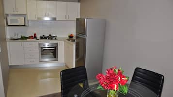Una cocina moderna con armarios blancos, electrodomésticos de acero inoxidable y una mesa de comedor con sillas.