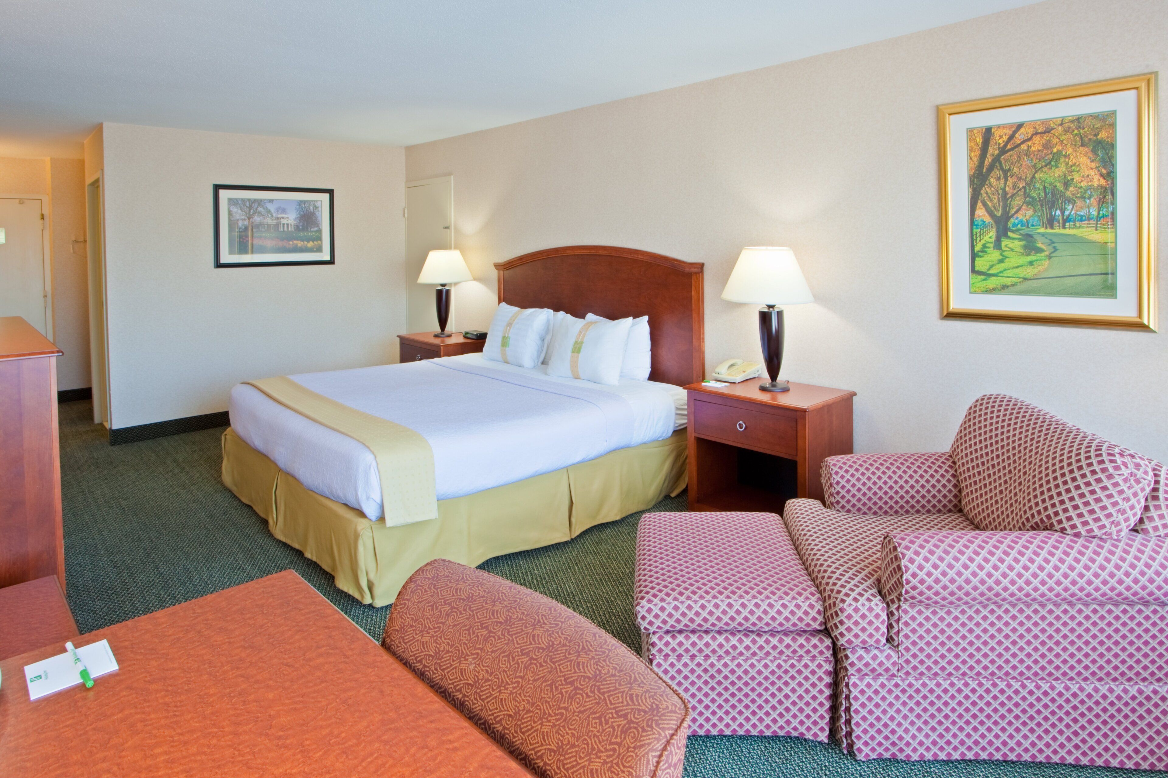 Une chambre d’hôtel comprenant un lit, deux tables de chevet, un bureau, une chaise et un canapé.