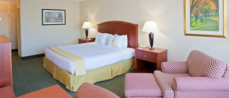 A hotel room with a bed, two bedside tables, a desk, a chair, and a couch.