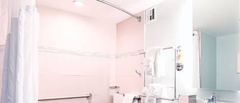 A bathroom with a shower, a sink, a mirror, and a towel rack.
