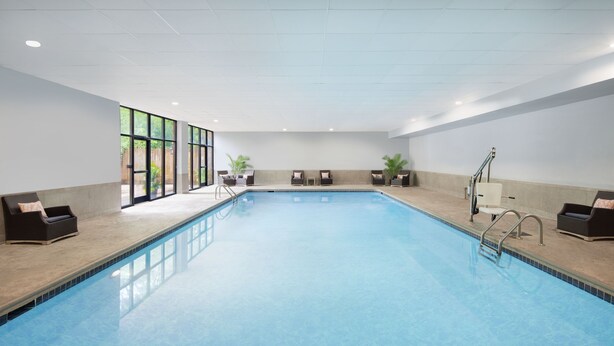 A large indoor swimming pool with clear blue water, surrounded by lounge chairs and potted plants. - Holiday Inn Charlottesville-Univ Area by IHG (Charlottesville)