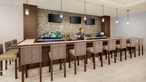 A bar area with a long counter, multiple bar stools, and a bartender. - Holiday Inn Charlottesville-Univ Area by IHG (Charlottesville)