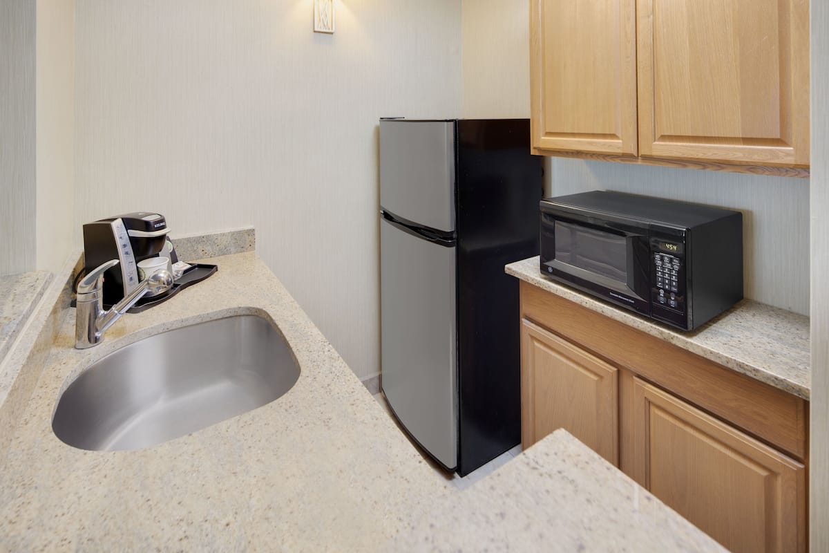 A kitchen with a stainless steel refrigerator, a microwave, a coffee maker, and a sink.
