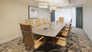 A conference room with a long table, six chairs, and three pendant lights. - Holiday Inn Charlottesville-Univ Area by IHG (Charlottesville)