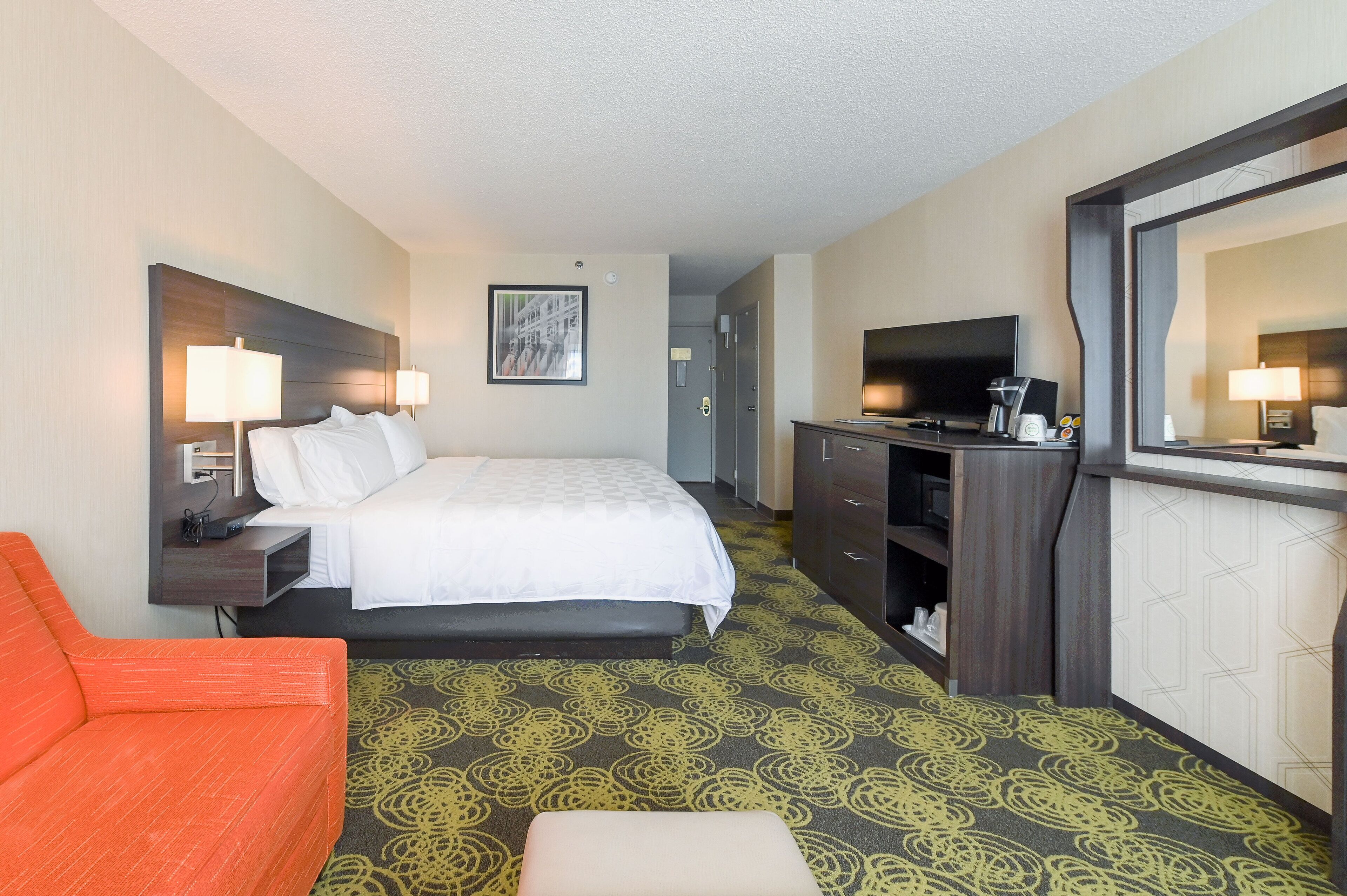 Une chambre d’hôtel comprenant un lit, un bureau avec une télévision, une chaise et une commode.
