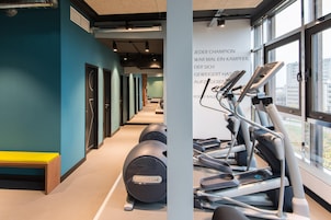 Ein Fitnessraum mit Trainingsgeräten, einer Bank und einer Wand mit Text.