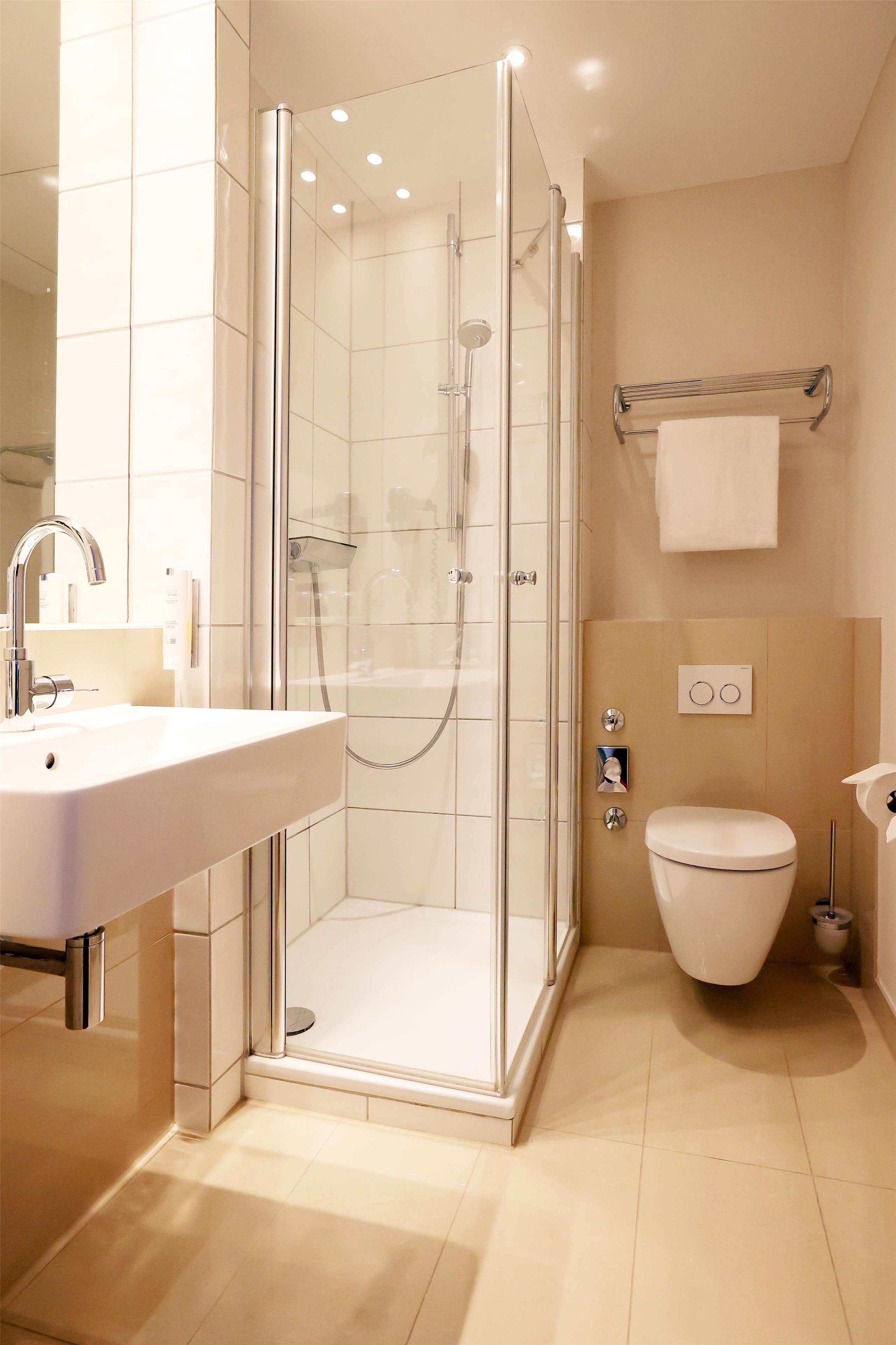Ein modernes Badezimmer mit einer begehbaren Glasdusche, einem weißen Waschbecken und einer Toilette.