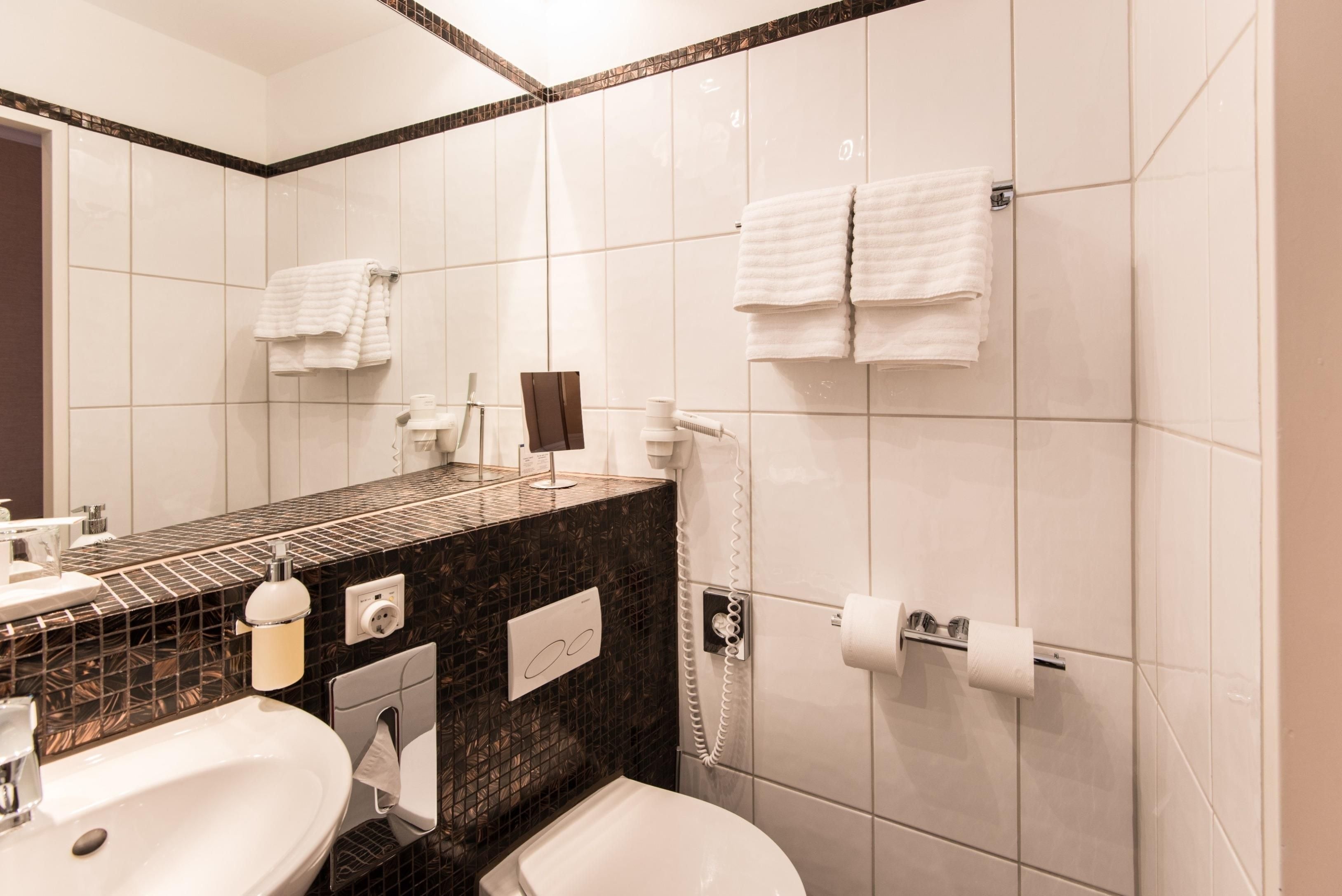 Ein Badezimmer mit Waschbecken, Spiegel, Toilette und Handtuchhalter.