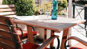 Una mesa de madera con una botella y vasos, una silla roja y un banco.