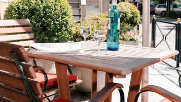 A wooden table with a bottle and glasses, a red chair, and a bench.