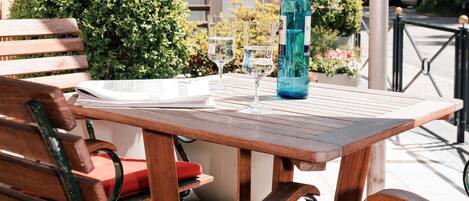 A wooden table with a bottle and glasses, a red chair, and a bench.