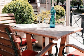 Una mesa de madera con una botella y vasos, una silla roja y un banco.