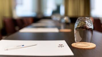 A conference table with a glass of water, a pen, and a coaster.