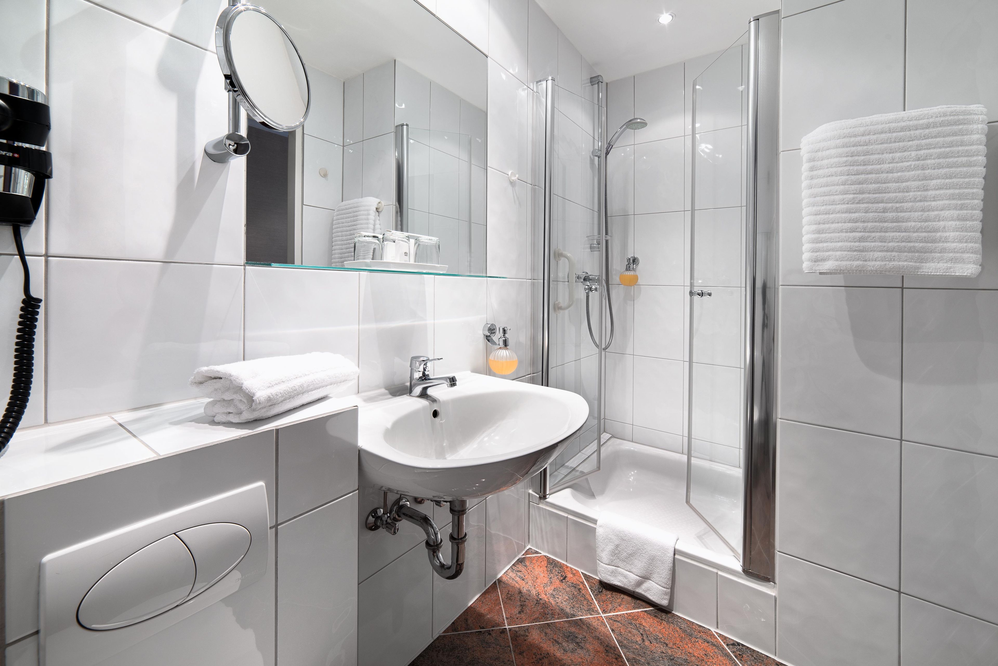 Un baño moderno con lavamanos, espejo y ducha.