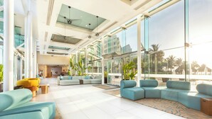 A spacious lobby with modern seating, large windows, and a view of palm trees.