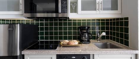 Una cocina con microondas de acero inoxidable, cafetera y tostadora.