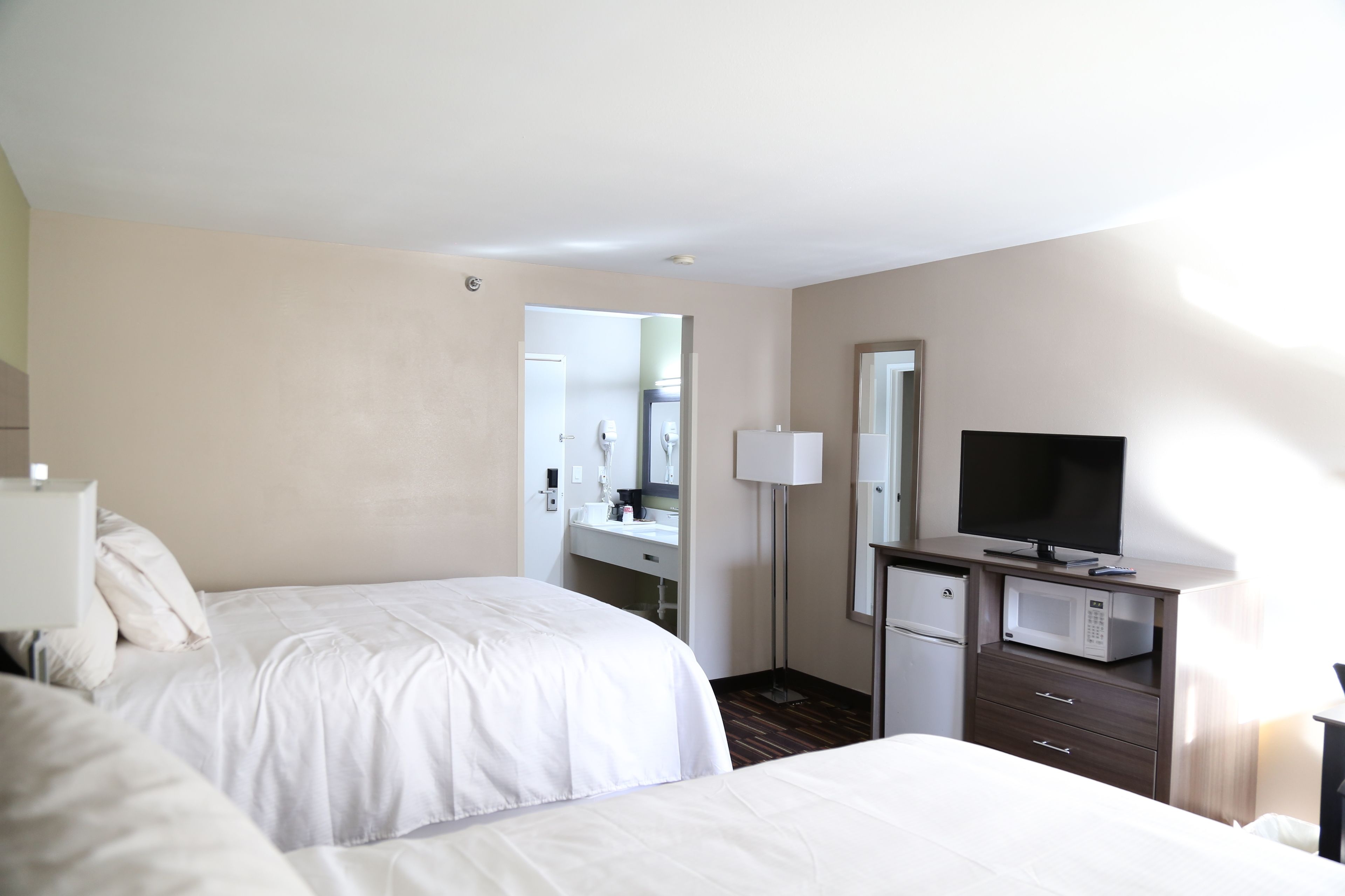 Une chambre d’hôtel avec deux lits, une télévision, un four à micro-ondes et une petite kitchenette.