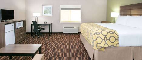 A hotel room with a bed, desk, chair, television, and a microwave.