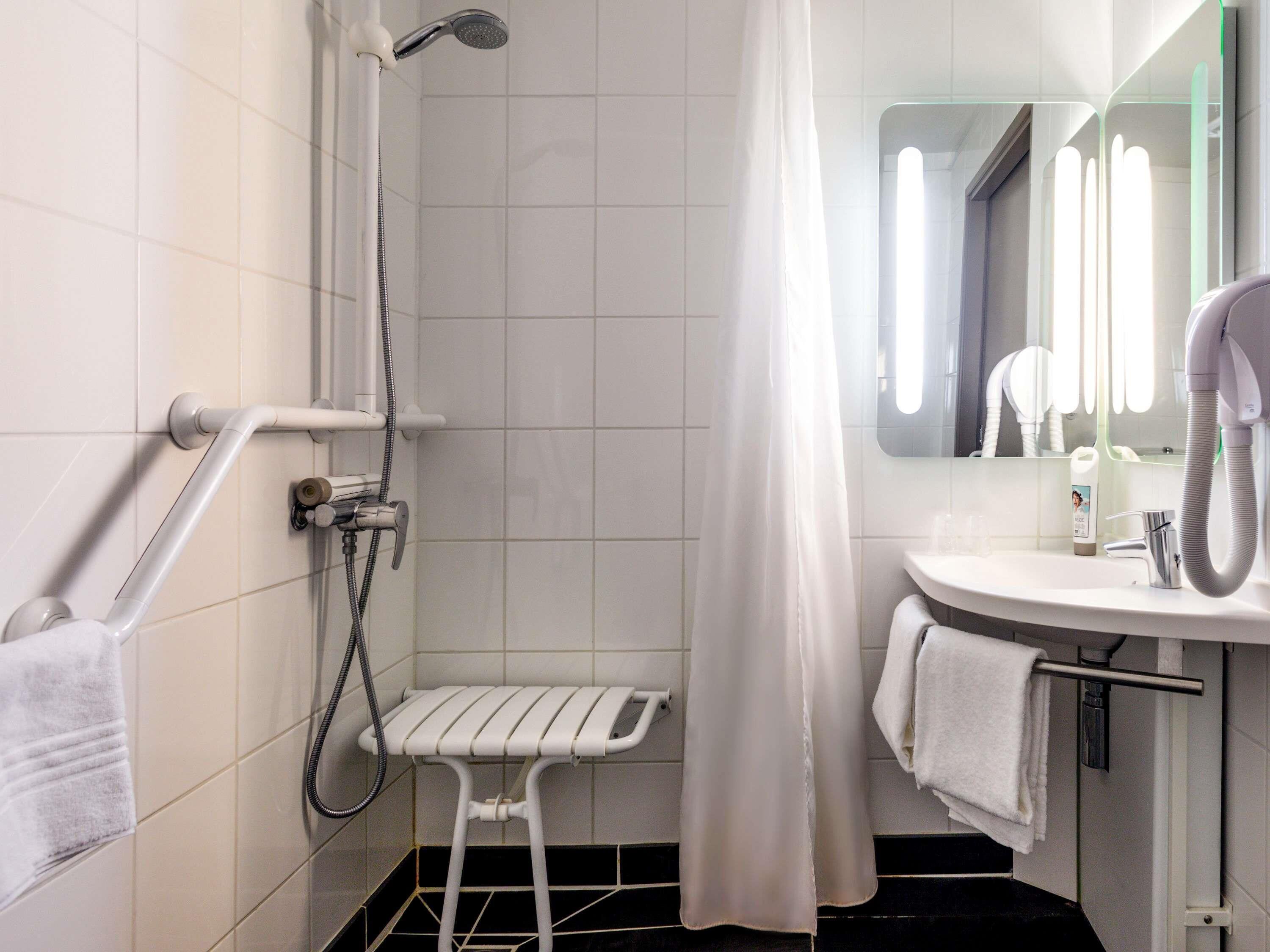 Une salle de bain équipée d’une douche, d’un lavabo, d’un miroir et d’un porte-serviettes.