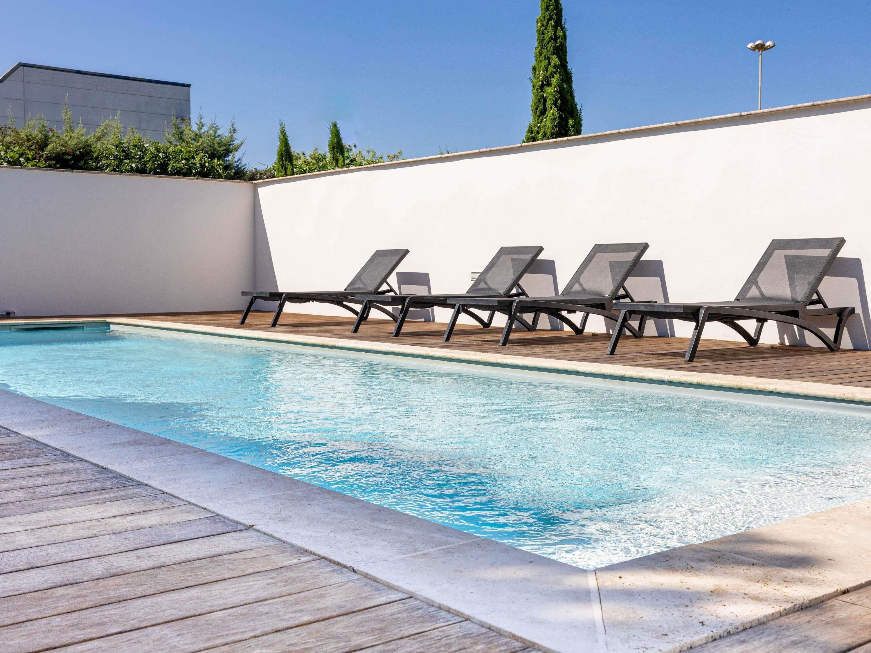 A swimming pool with lounge chairs and a wooden deck.