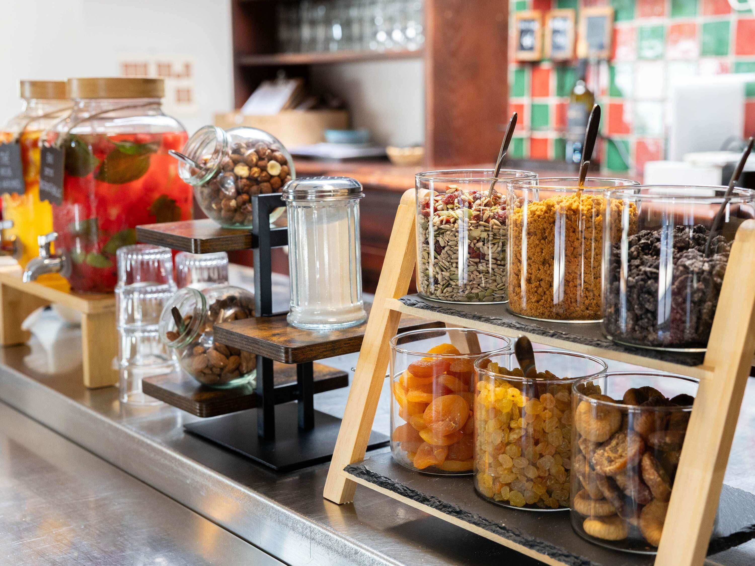 A food display with various jars of nuts, dried fruits, and granola.