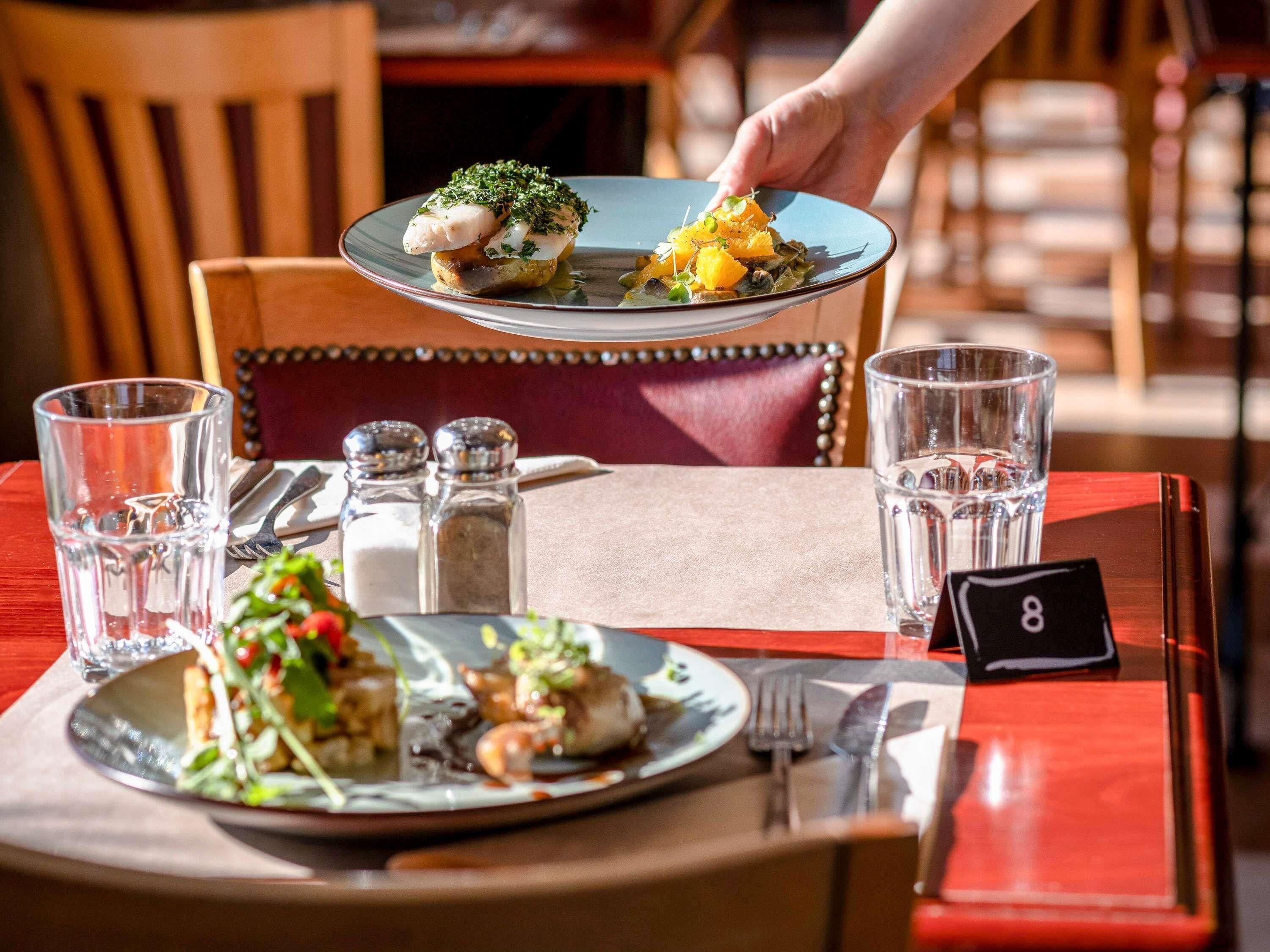 A dining table set with plates of food, glasses, and a numbered placemat.