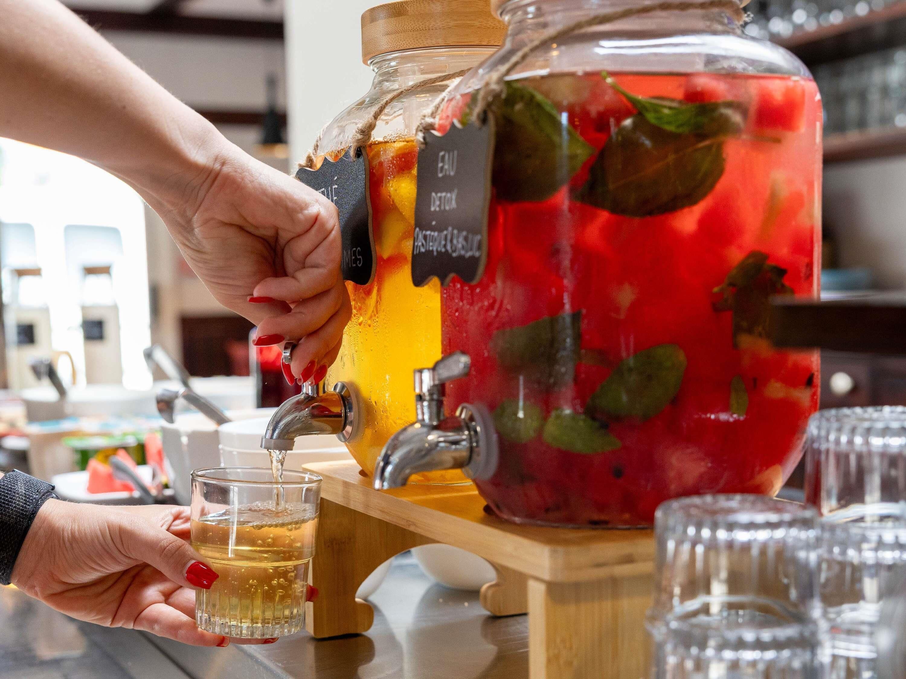 Une personne verse une boisson d’une grande carafe dans un verre.
