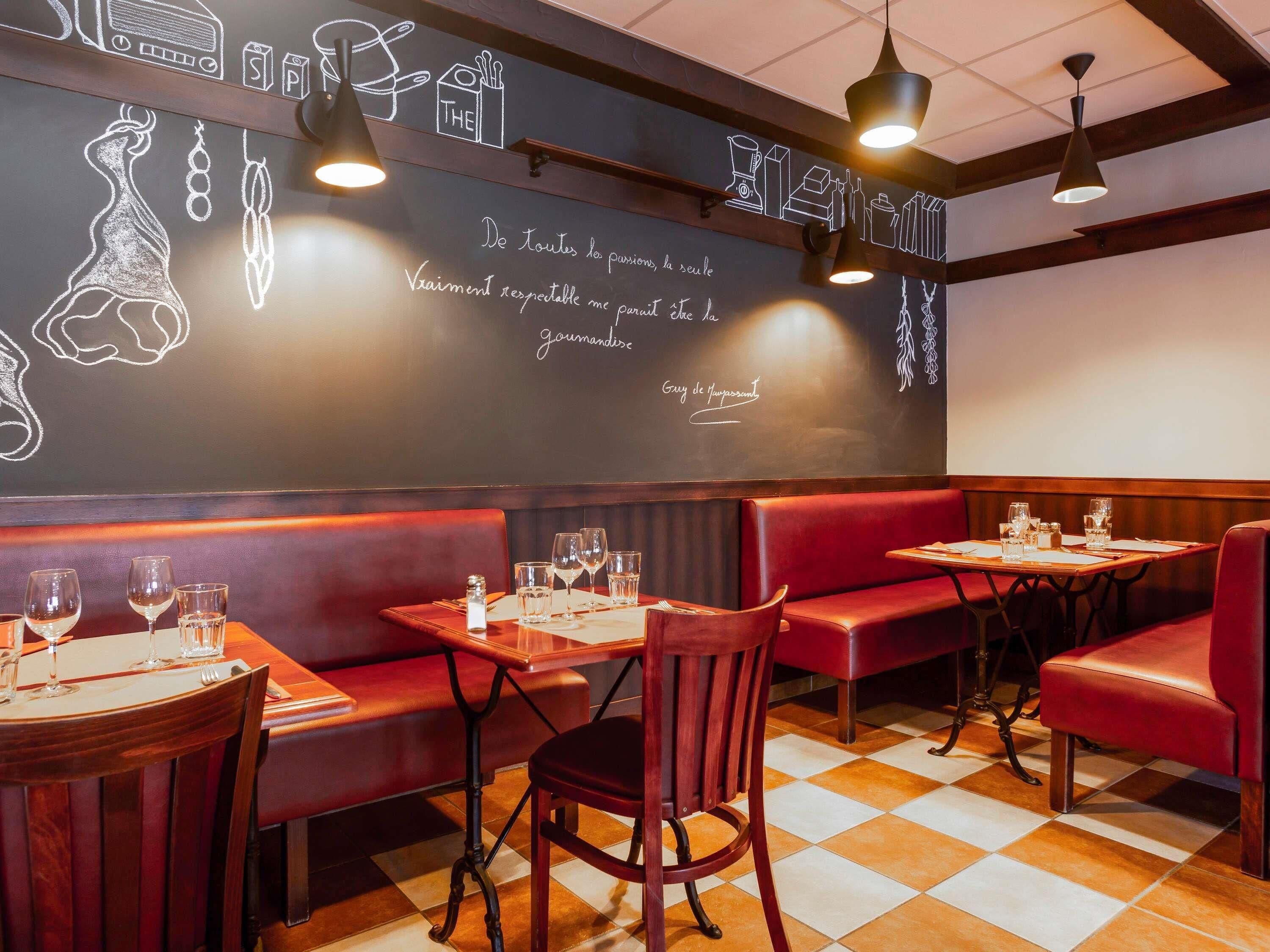 Ein Restaurantinnenraum mit Sitzecken, Tischen und einer Kreidetafel mit der Speisekarte.