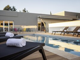 Una piscina al aire libre de temporada, sillones reclinables de piscina