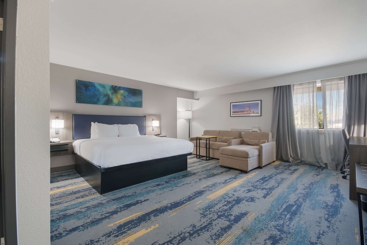 Habitación de hotel con una cama grande, un escritorio, una silla, un sofá y vistas al exterior.