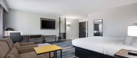 Una habitación de hotel con una cama, un sofá, un escritorio y una televisión.