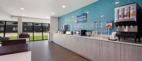 Un área de cocina moderna con salpicadero de azulejos azules, una cafetera y un microondas.