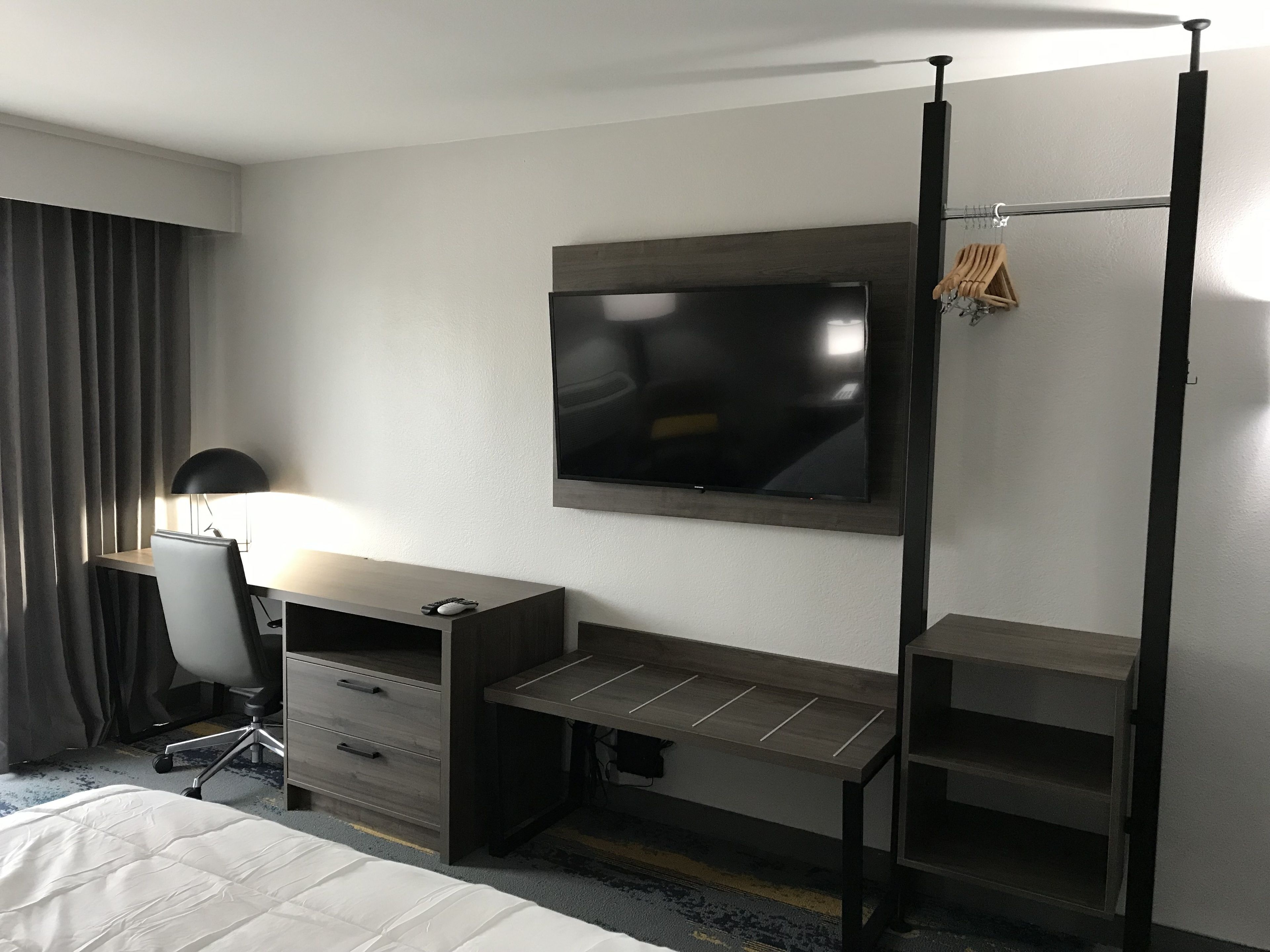 A hotel room with a bed, a desk with a computer, a TV, and a chair.
