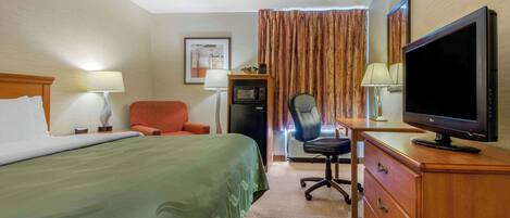 A hotel room with a bed, desk, chair, television, and a microwave.