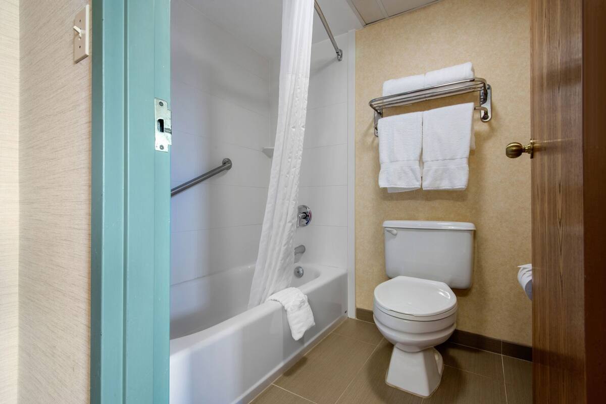 A bathroom with a bathtub, toilet, and towel rack.