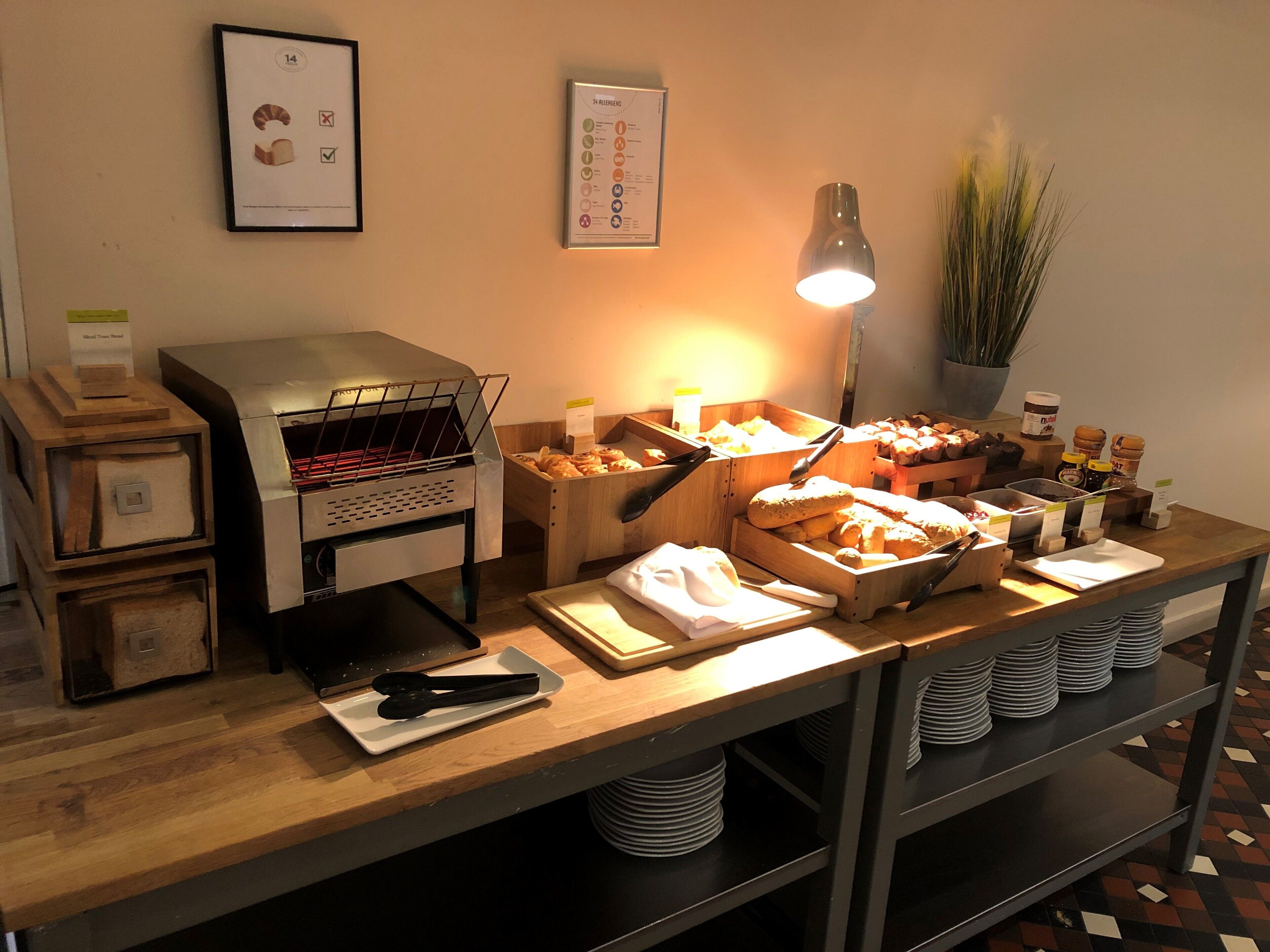Montaje de bufé con diversos alimentos, una máquina de café y una planta en la pared.