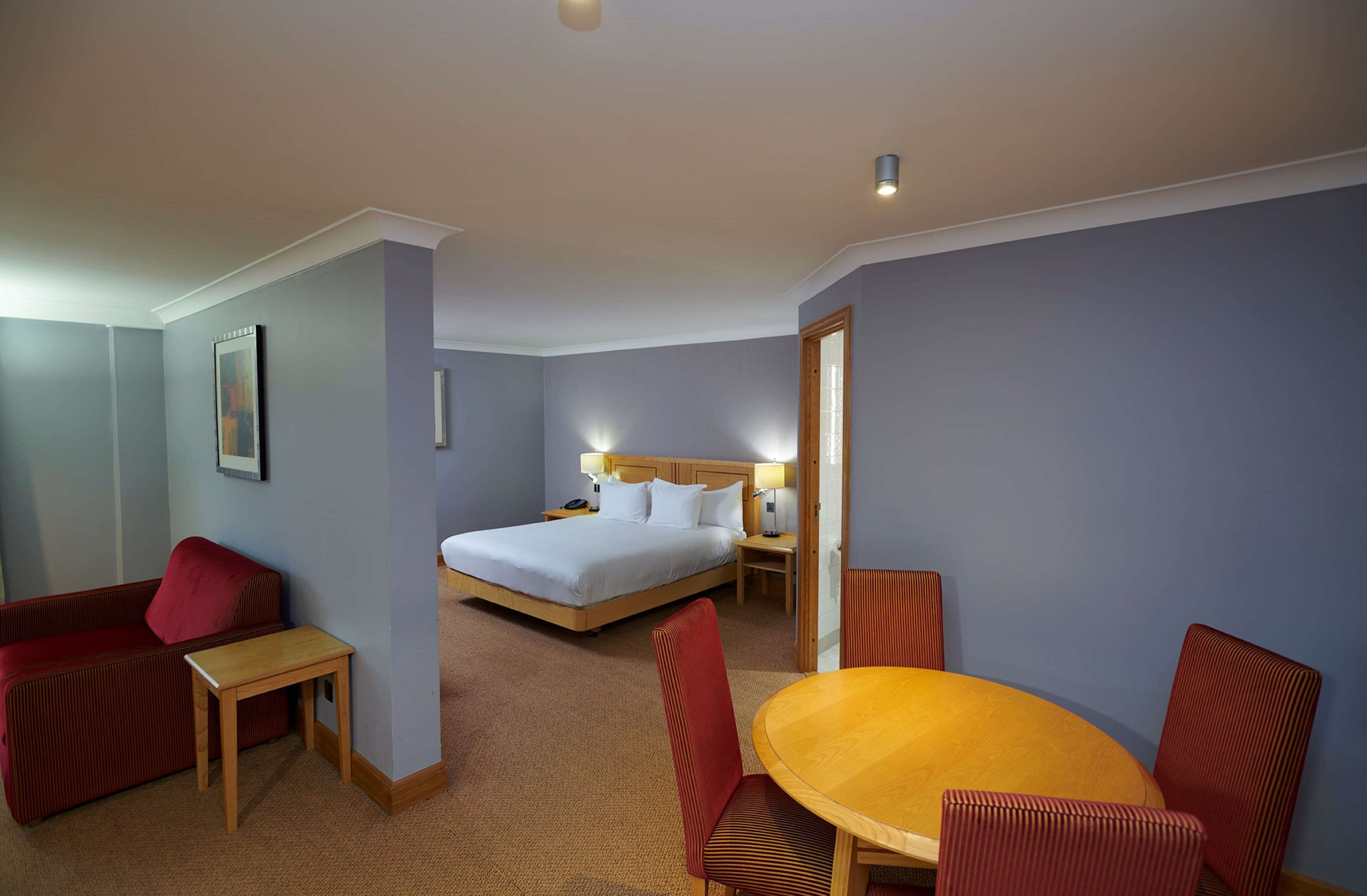 Une chambre d’hôtel comprenant un lit, une petite table, une chaise, un canapé et une table à manger avec des chaises.