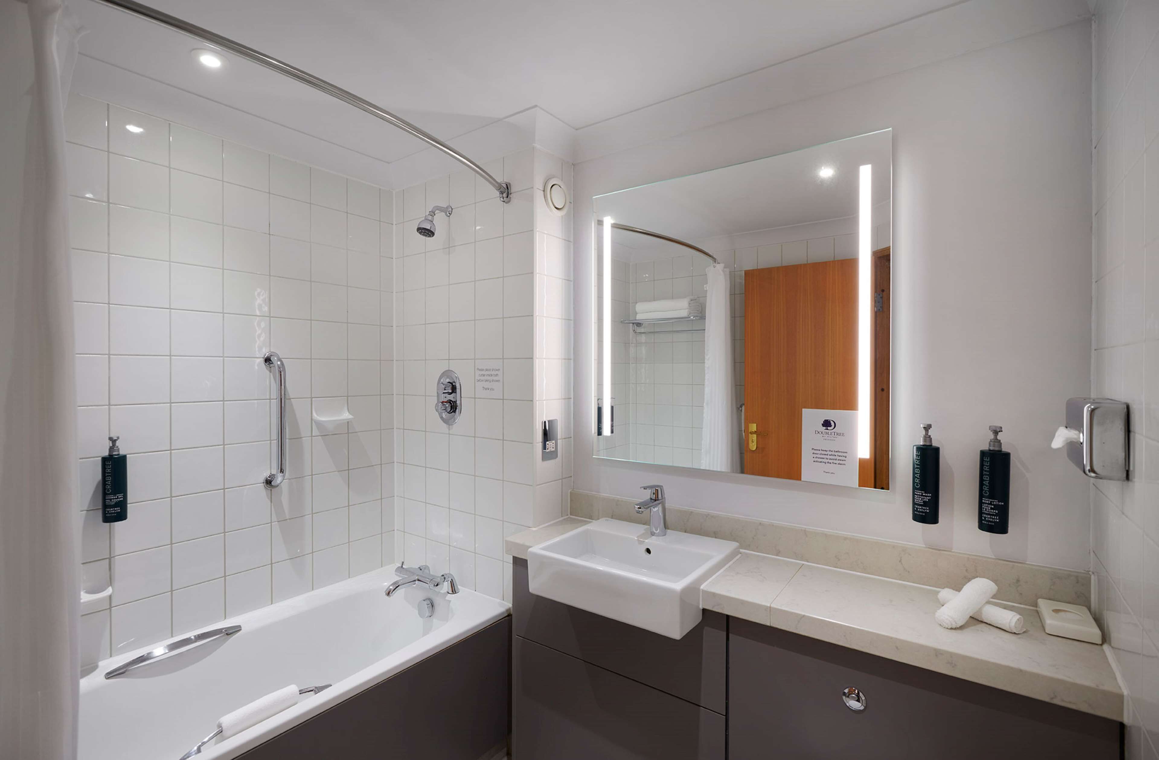 A modern bathroom with a bathtub, a sink, a shower, and a large mirror.