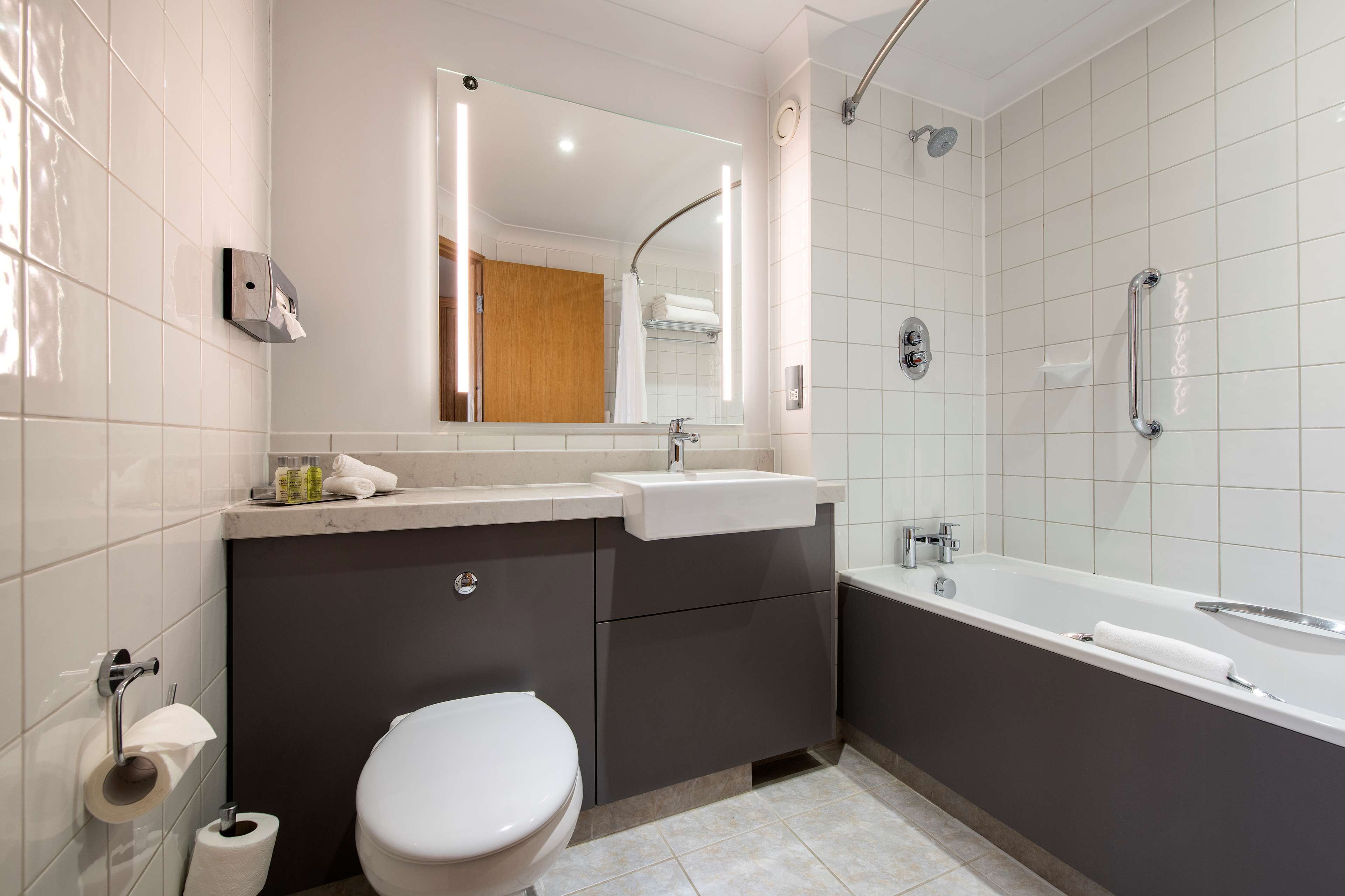 A modern bathroom with a toilet, sink, vanity, and bathtub.